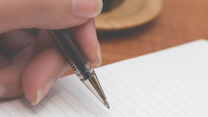 ボールペンでメモを取ろうとする手