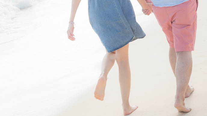 幸せそうに浜辺を歩くカップル