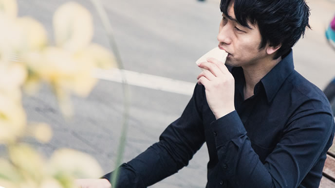 不満ありげでサンドイッチを食べる男性