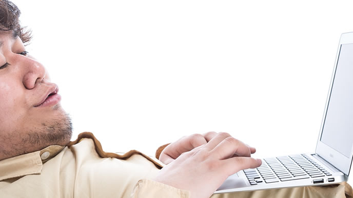 寝転がりパソコンをする男性