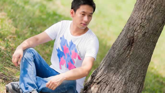 木陰で休憩するTシャツ男性