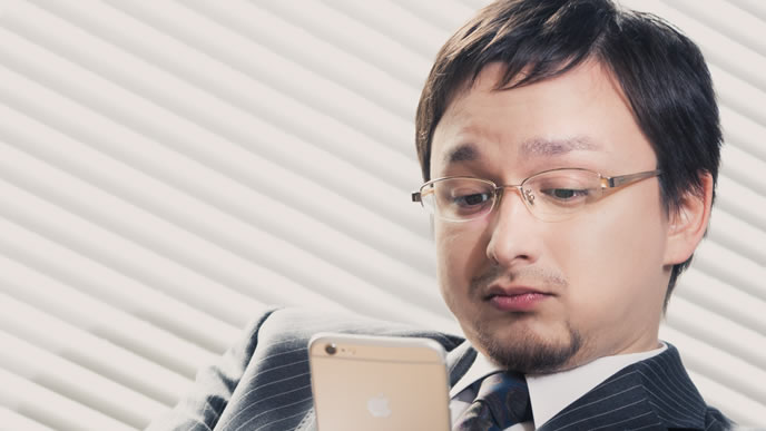 憂鬱な気分で携帯電話を眺めている男性