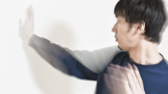 壁に張り手をし続ける男性