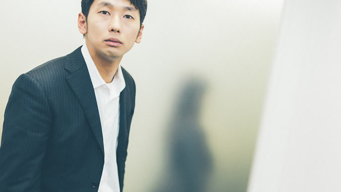 自分の噂話を聞き呆然とする男性