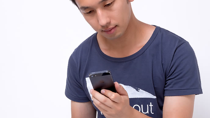 スマホで調べ物をする男性