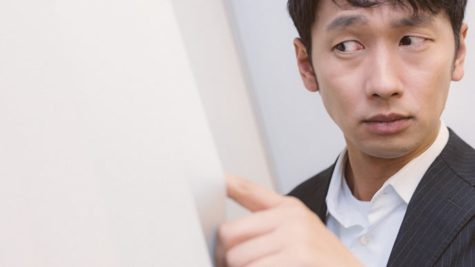 会社の窓から外をのぞく男性