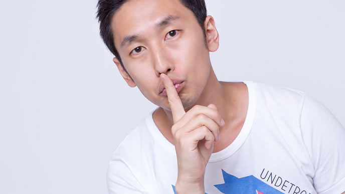 秘密を守るように仕草で表す男性