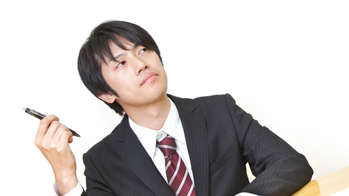 ペンを持って考え込む男性