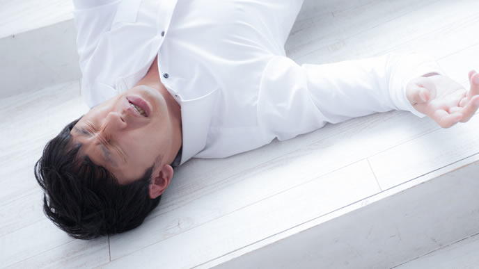 体調不良で床にころがる男性