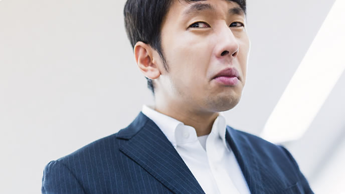 不満気な表情で話しを聞く男性