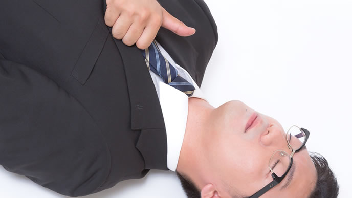 仕事に疲れて倒れながらもアピールする男性
