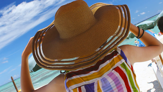 まぶしい日差しで帽子をかぶる女性