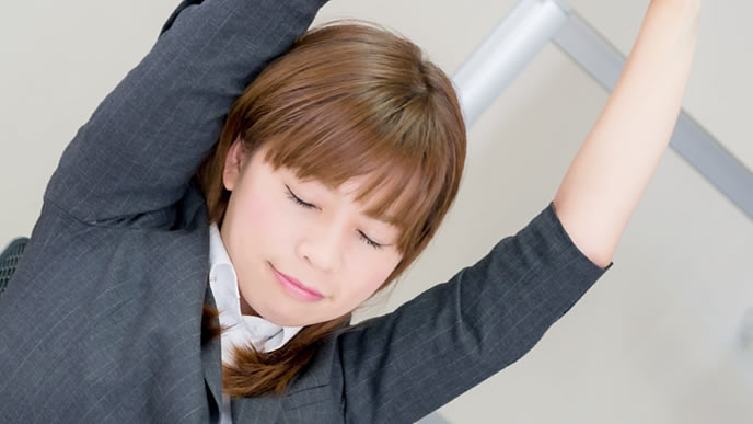 伸びをして疲れを和らげる女性