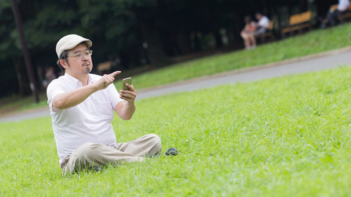 会社の昼休みにスマホで遊ぶ中年男性