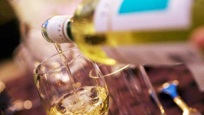 白ワインをグラスに注いでいる