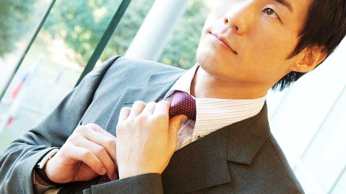 ネクタイを締め直して身だしなみを整えているスーツを着たビジネスマン