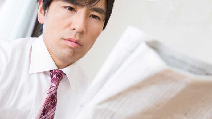 電車の中で新聞を読んでる男性