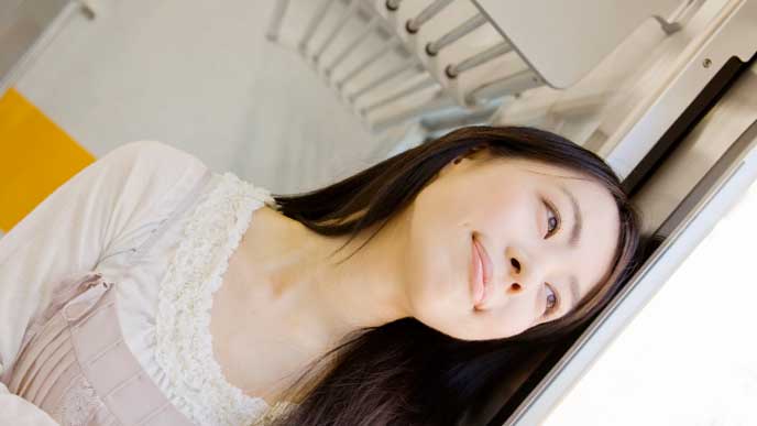 電車の中から外を見ている女性