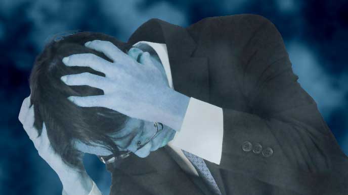 ストレスで頭を抱えているスーツを着た男性