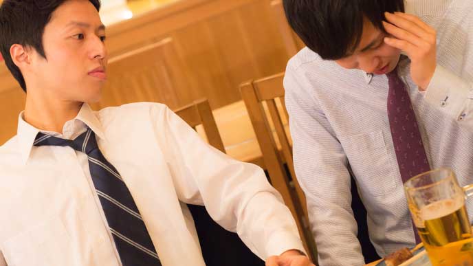 居酒屋で上司と話してる困ってるスーツを着た男性