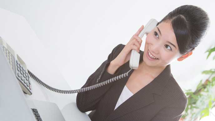 笑顔で電話を受けているスーツを着た女性社員
