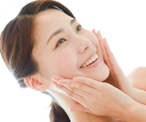 頬を触りながら笑顔の女性