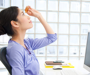 パソコンの前で点眼する女性