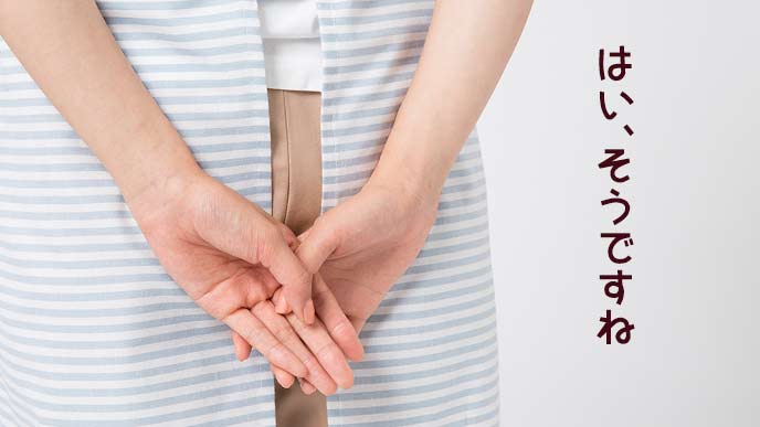 背中で手を組んで立つ保育士