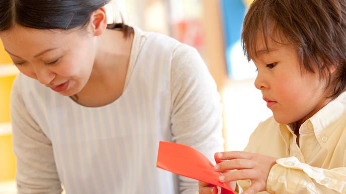 子供に折り紙を教える保育士