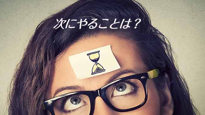 額に貼った砂時計を気にする女性