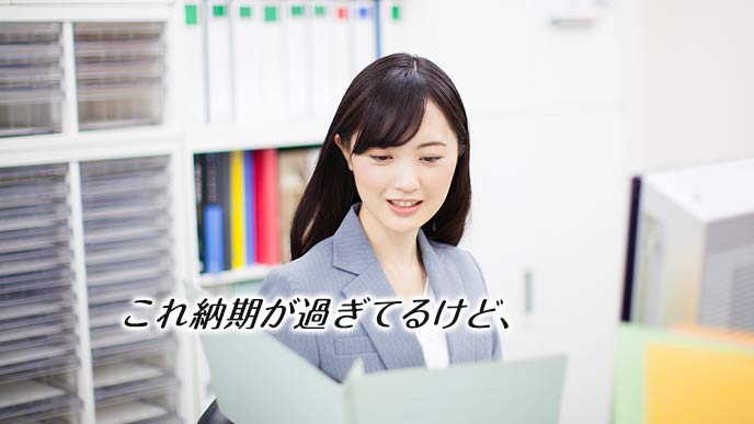 ファイリングを見て納期遅れを確認する女性社員