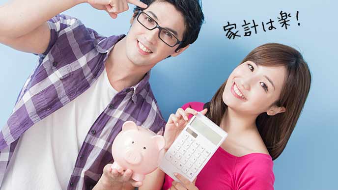 夫婦並んで貯金箱と電卓を持つ