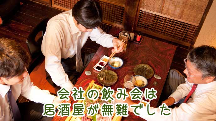 居酒屋のテーブル席で会社の飲み会を楽しむ
