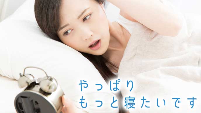 目覚まし時計に起こされる睡眠不足の女性