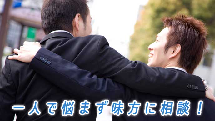 同僚と肩を組んで歩いているサラリーマン