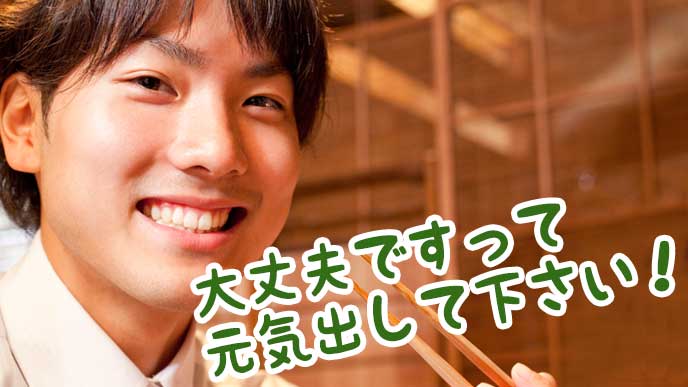居酒屋の席で励ます男