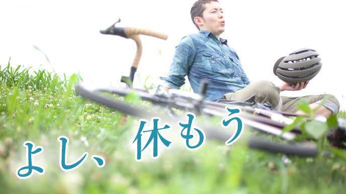 サイクリングを楽しみ、野原の上で休む男