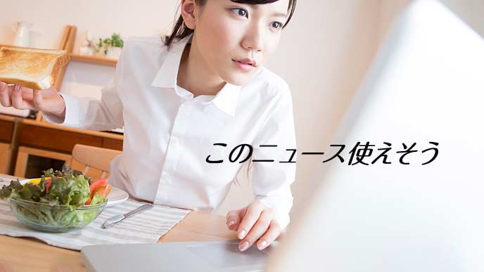 朝食を食べながらラップトップでニュースを調べる女性