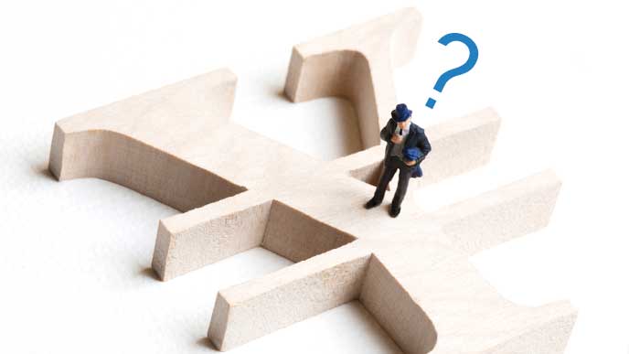 円マークの上で考え込むサラリーマンの人形