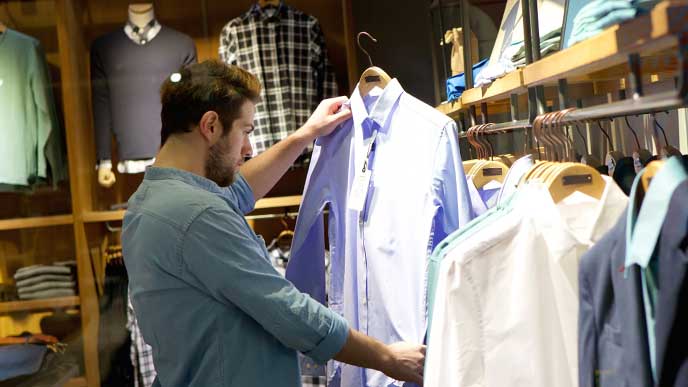 洋服屋で売られているワイシャツをじっくり見る男