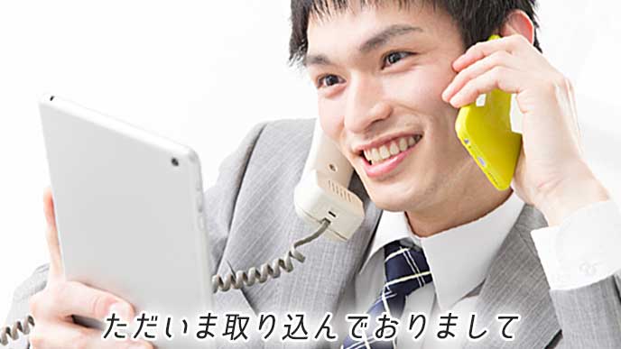 タブレットPCを見ながら電話応対と忙しいビジネスマン