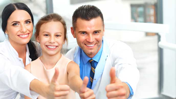 子供と一緒にサムズアップする歯科医と歯科助手
