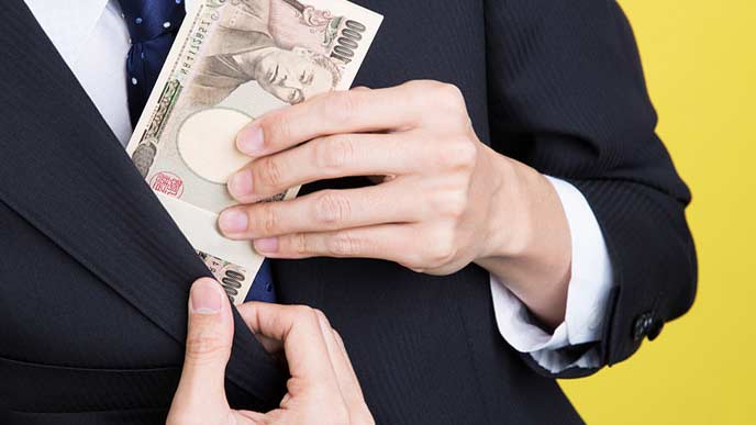 懐に札束を入れるビジネスマン