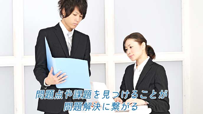 資料のファイルとノートパソコンを使って仕事を進める会社員達