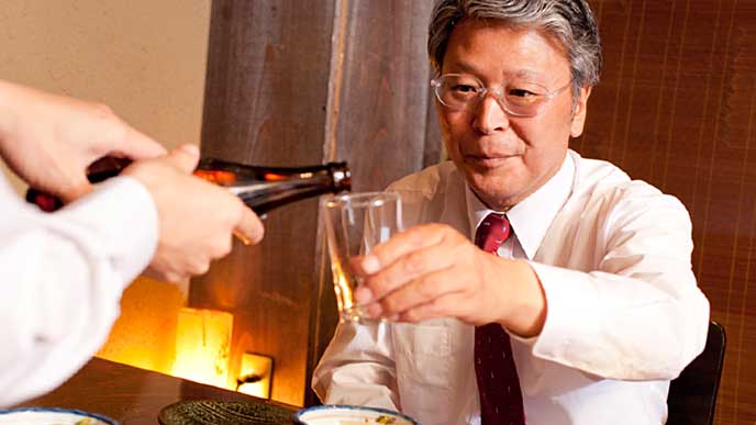 接待の会食で相手にビールを注ぐ