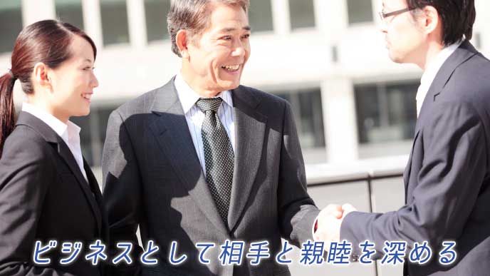 取引先の社長と握手をするビジネスマン