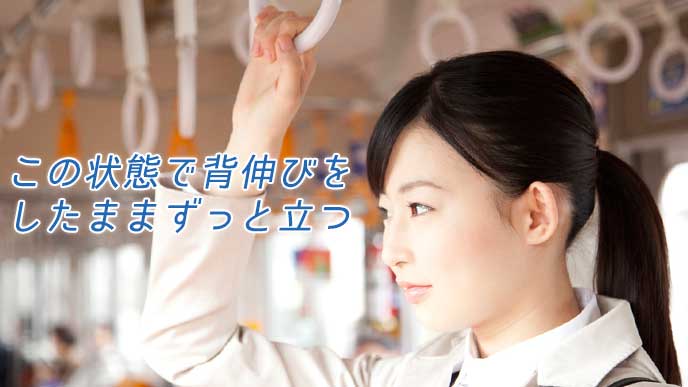 電車での通勤中につり革を掴む女性