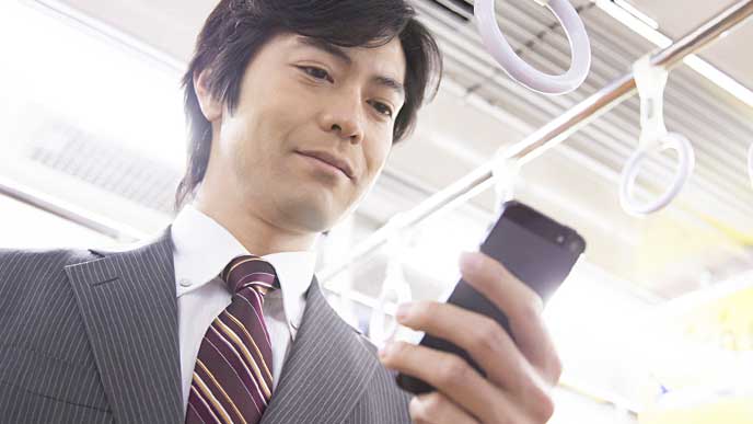 通勤中にスマホを見るサラリーマン