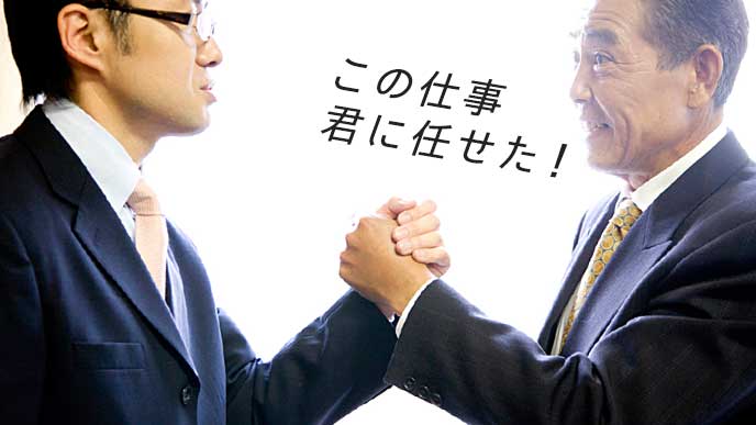 部下と力強く握手を交わす上司