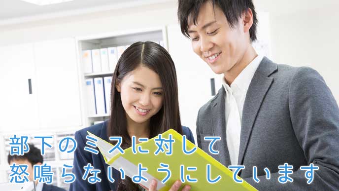 資料のファイルを開き部下に仕事のアドバイスをするサラリーマン
